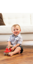 boy playing with toy truck in the living room, sitting and smiling for the camera
