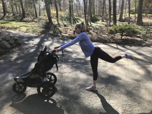 woman holding jogging stroller and kicking behind her