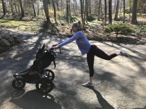 woman holding jogging stroller and kicking behind her