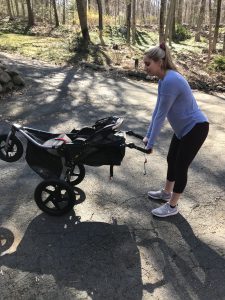 woman pushing down on a jogging stroller handles