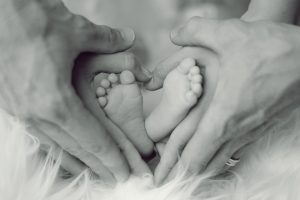 parents holding their babies feet in a heart shape with their hands; preparing for a new baby