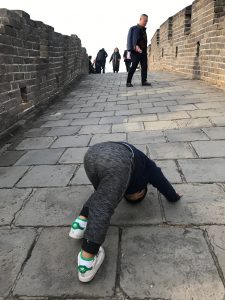 Toddler doing a sun salutation on the Great Wall.
