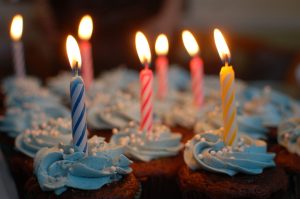 frosted cupcakes with lighted birthday candles