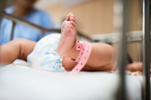 baby in a newborn hospital nursery with pink hospital band--preparing for a new baby