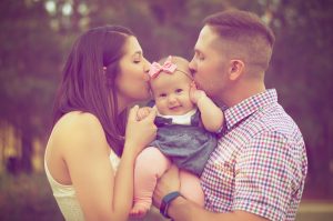 loving couple with baby girl with pink bow--preparing for a new baby